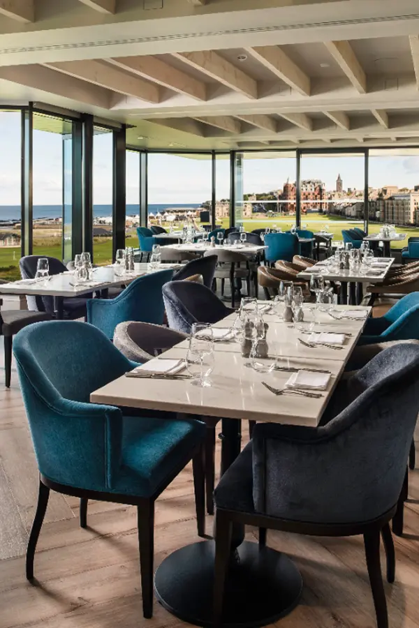 Modern restaurant with teal velvet chairs and coastal view